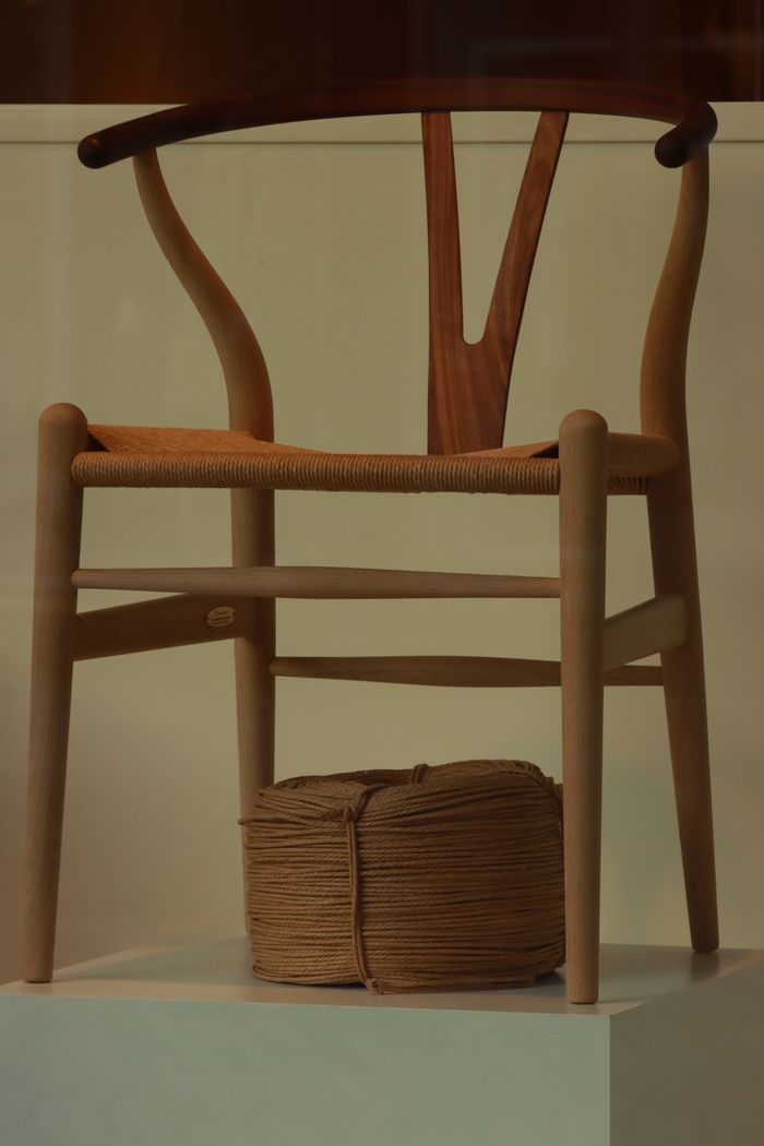 Elegant wooden chair with rope spool, minimalist design, warm tones.