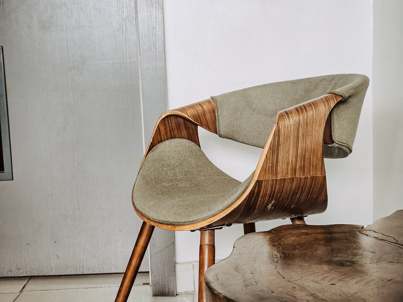 Stylish wooden chair with curved design set in a minimalist indoor space, highlighting modern interior aesthetics.