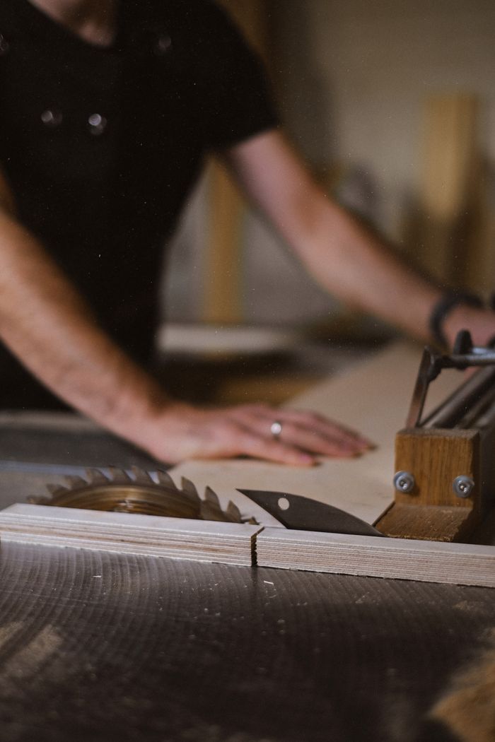 services-img Unrecognizable blurred male master cutting wooden plank using table saw with sharp knives while working in professional workshop with special instruments
