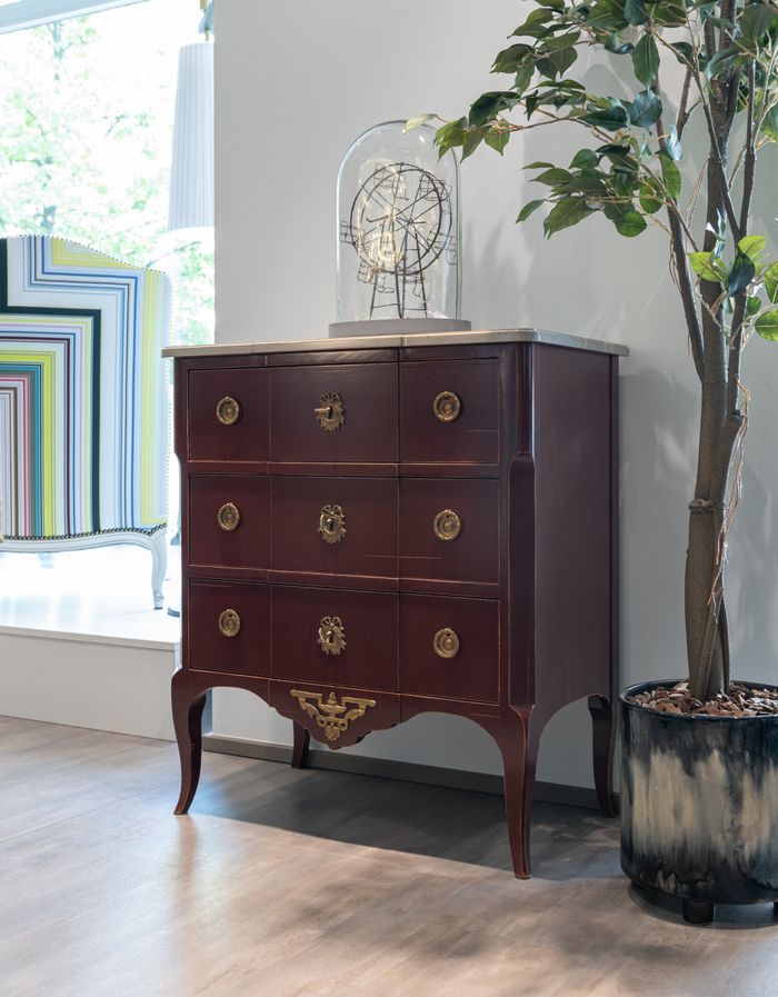 A stylish vintage wooden cabinet with brass handles in a contemporary interior setting.